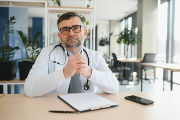 Portrait of serious senior doctor in eyeglasses and in white coat.