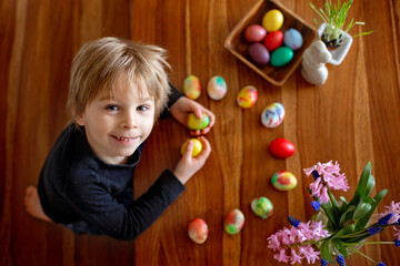Fototapeta na wymiar Little blond toddler boy child coloring easter eggs at home, Czech Republic tradition