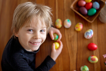Fototapeta na wymiar Little blond toddler boy child coloring easter eggs at home, Czech Republic tradition