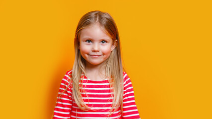 Closeup portrait of adorablel little girl in red dress looking at camera with happy carefree smile