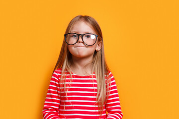 Funny smiling child school girl with glasses on yellow background. Back to school.