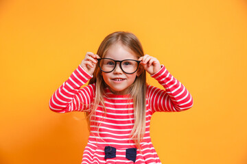 Close-up portrait of blond funny girl in red dress and glasses on yellow background