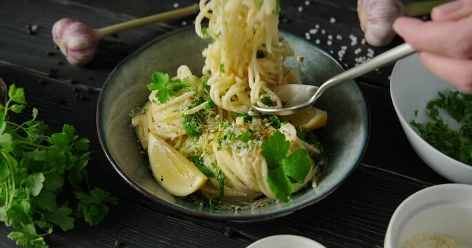 Eating Lemon pasta, Pasta al Limone, person tasting spaghetti with white cream sauce, lemon zest and parmesan cheese, using fork and spoon, 4k footage, high quality horizontal video clip