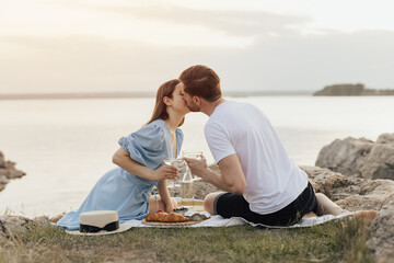 Romantic picnic of couple in love on beach at sunset. They kissing and feeling love. The concept of leisure, privacy, communication and vacation. Copy space.