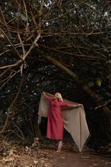 A fifty-year-old Caucasian woman with blonde hair is dancing against a natural landscape backdrop. The concept of balance between nature and humans. Beautiful aging.