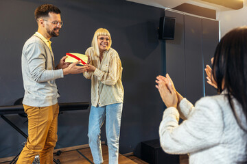 Businesswoman receiving award from businessman in front of business professionals, applauding at business seminar in office building