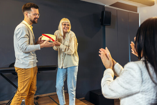 Businesswoman receiving award from businessman in front of business professionals, applauding at business seminar in office building