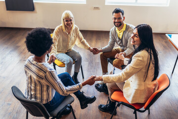 Group of people sitting in a circle are participating in a support meeting.