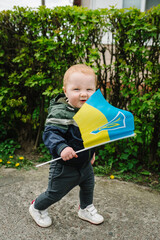 Flag day. Ukrainians against war. Ukrainian flag blue and yellow in hands kid, child. Happy baby boy. Independence Day. Constitution day. Family, unity, support. No war. Winner. Closeup.