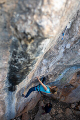 A woman climbs a rock