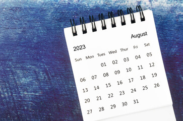 The August Monthly desk calendar for 2023 year on old blue wooden background. - obrazy, fototapety, plakaty