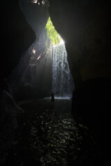 Silhouette of a man standing in a cave with a waterfall in the background