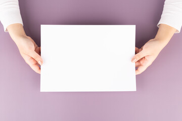 a woman holds a blank sheet of paper in her hands. Advertising space