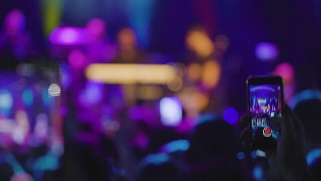 Spectators photograph the singer who performs on stage with their mobile phone