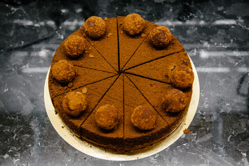 Chocolate cake cut into slices lies on a marble table