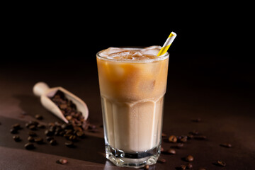 Cappuccino with Ice cubes in a tall Glass against a black background. Iced Coffee with milk in a glass