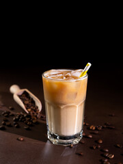Cappuccino with Ice cubes in a tall Glass against a black background. Iced Coffee with milk in a glass