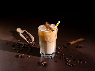 Cappuccino with Ice cubes in a tall Glass against a black background. Iced Coffee with milk in a...