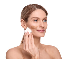 Woman applying foundation on face with makeup sponge against white background