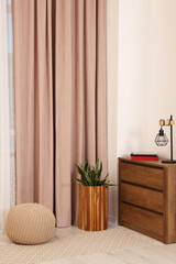 Stylish room interior with chest of drawers, houseplant and curtains