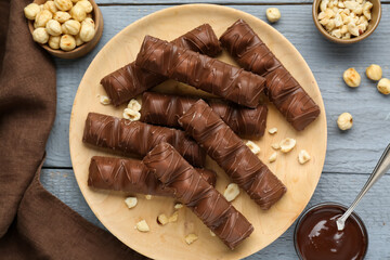 Sweet tasty chocolate bars with nuts on grey wooden table, flat lay