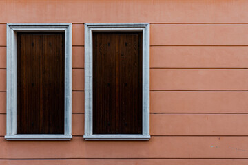 White windows covered with wooden boards of a pink building