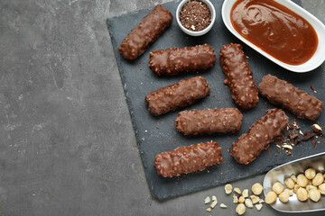 Tasty chocolate bars with caramel and nuts on light grey table, flat lay. Space for text
