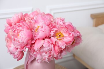 Beautiful bouquet of pink peonies in vase on wooden table indoors, closeup