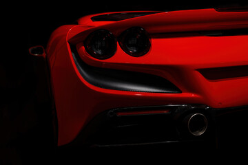 Close-up of rear lights of Red sports car on the dark background.