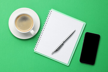 Ballpoint pen, notebook and smartphone on green background, flat lay