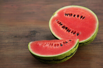 Delicious cut ripe watermelons on wooden table. Space for text