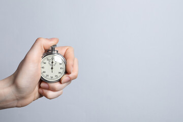 Woman holding vintage timer on light grey background, closeup. Space for text