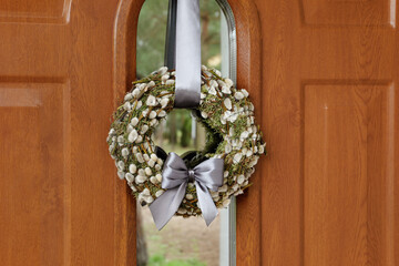 Wreath made of beautiful willow branches and grey bow on wooden door © New Africa