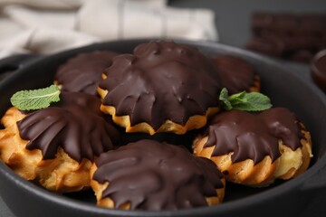 Delicious profiteroles with chocolate spread and mint in frying pan, closeup