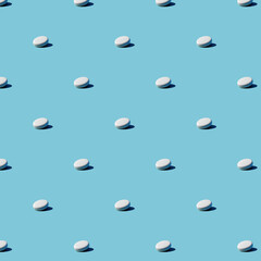 White pills on a blue background. Seamless pattern for background. Flat design medical pharmacy for website presentation packaging, flyer, business card cover.