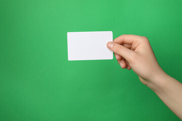 Woman holding blank gift card on green background, closeup