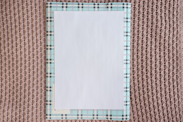Blank sheet of paper with office folder on knitted plaid