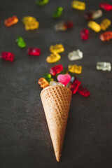Vertical closeup shot of an ice cream cone filled with gummy bears and jellies