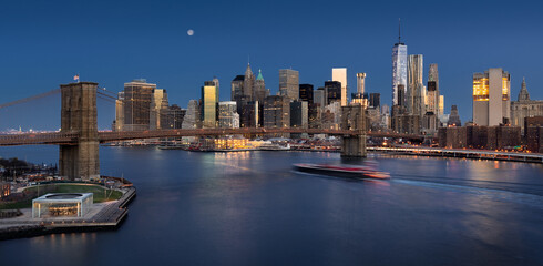 Fototapeta na wymiar Cityscape of the Brooklyn Bridge and skyscrapers of the Financial District at dawn with moonrise. Lower Manhattan, New York City