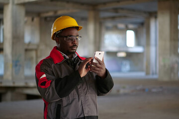 African american workman with smartphone at construction site