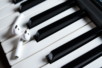 Closeup of wireless earphones on black and white piano keys