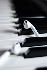 Vertical closeup of wireless earphones on black and white piano keys