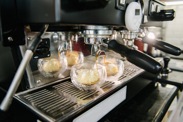 Fototapeta na wymiar Coffee machine. Coffee with foam is poured from the holder into glass cups. Ice cream scoops in glasses. Steam is coming