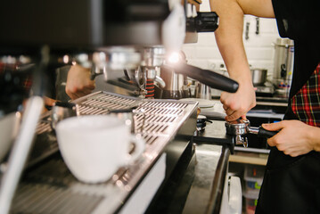 A barista in a cafe presses coffee into a holder and prepares to brew coffee.