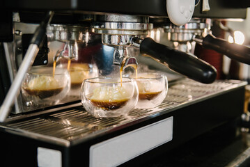 Coffee machine. Coffee with foam is poured from the holder into glass cups. Ice cream scoops in glasses. Steam is coming
