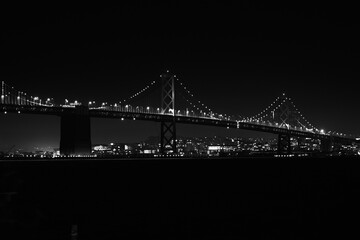 Grayscale of the shiny  Oakland Bay Bridge at night in San Francisco, USA