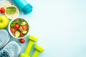 Healthy lifestyle and diet food background. Sport shoes, dumbell and healthy food on blue. Flat lay...