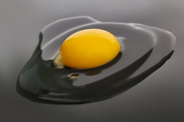 Broken egg on a black background. The contents of the egg on the plane. A raw egg.