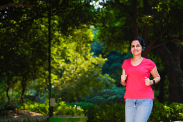 young indian woman with earphones listening music during jogging at park.