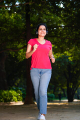 young indian woman with earphones listening music during jogging at park.